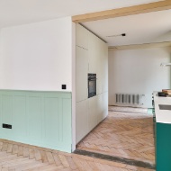 Open-plan kitchen and entrance area with green accenting features
